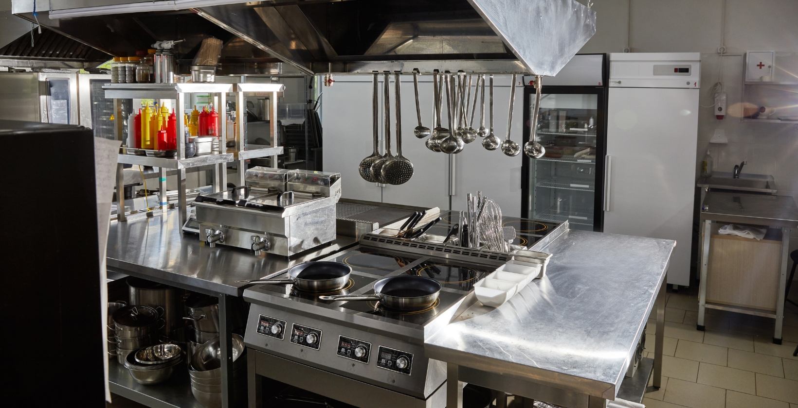 Commercial catering gas services UK Stainless steel commercial kitchen in the UK with a gas cooking range, fryers and extraction canopy