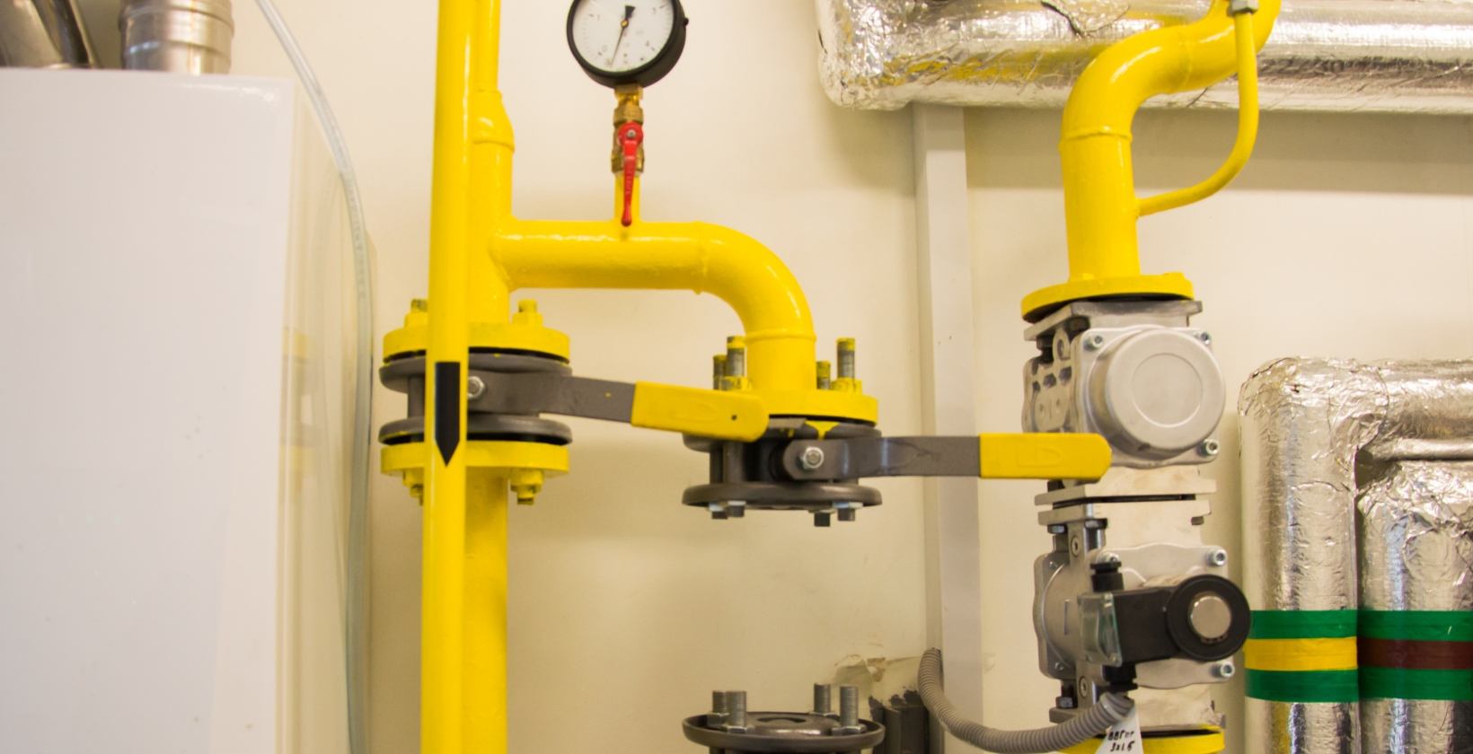 Commercial gas installation UK Commercial gas installation in a UK plant room: yellow gas pipework with a pressure gauge, flanged isolation valves and a gas train