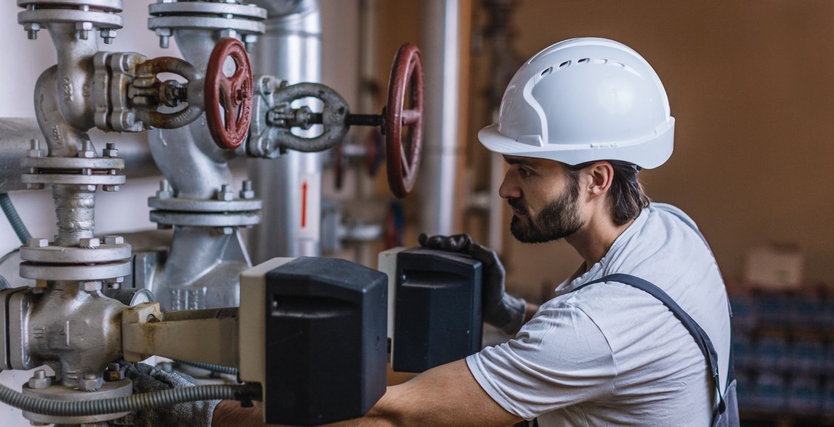 Gas testing and gas purging UK Gas engineer in a white hard hat checking valves and gauges on commercial gas pipework during a tightness test in the UK